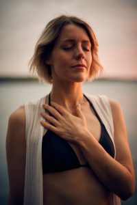Woman with her eyes closed with her hand on her chest